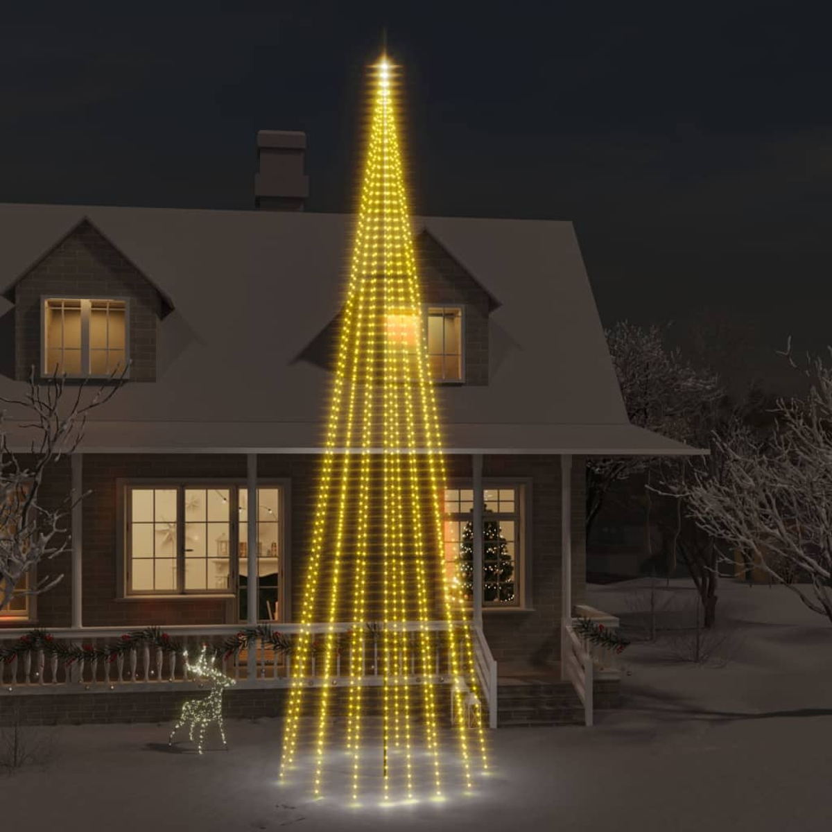 Ein Haus mit einem leuchtenden Weihnachtsbaum aus Lichtern. Eine Hirschdekoration steht im Schnee vor der Veranda.