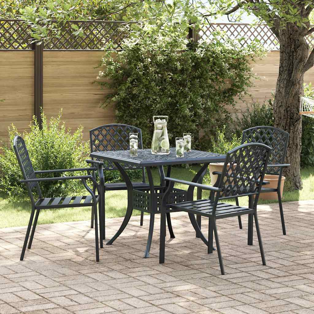 Un juego de patio con una mesa y cuatro sillas. Hay bebidas en la mesa. La escena es en un jardín con una valla y vegetación.