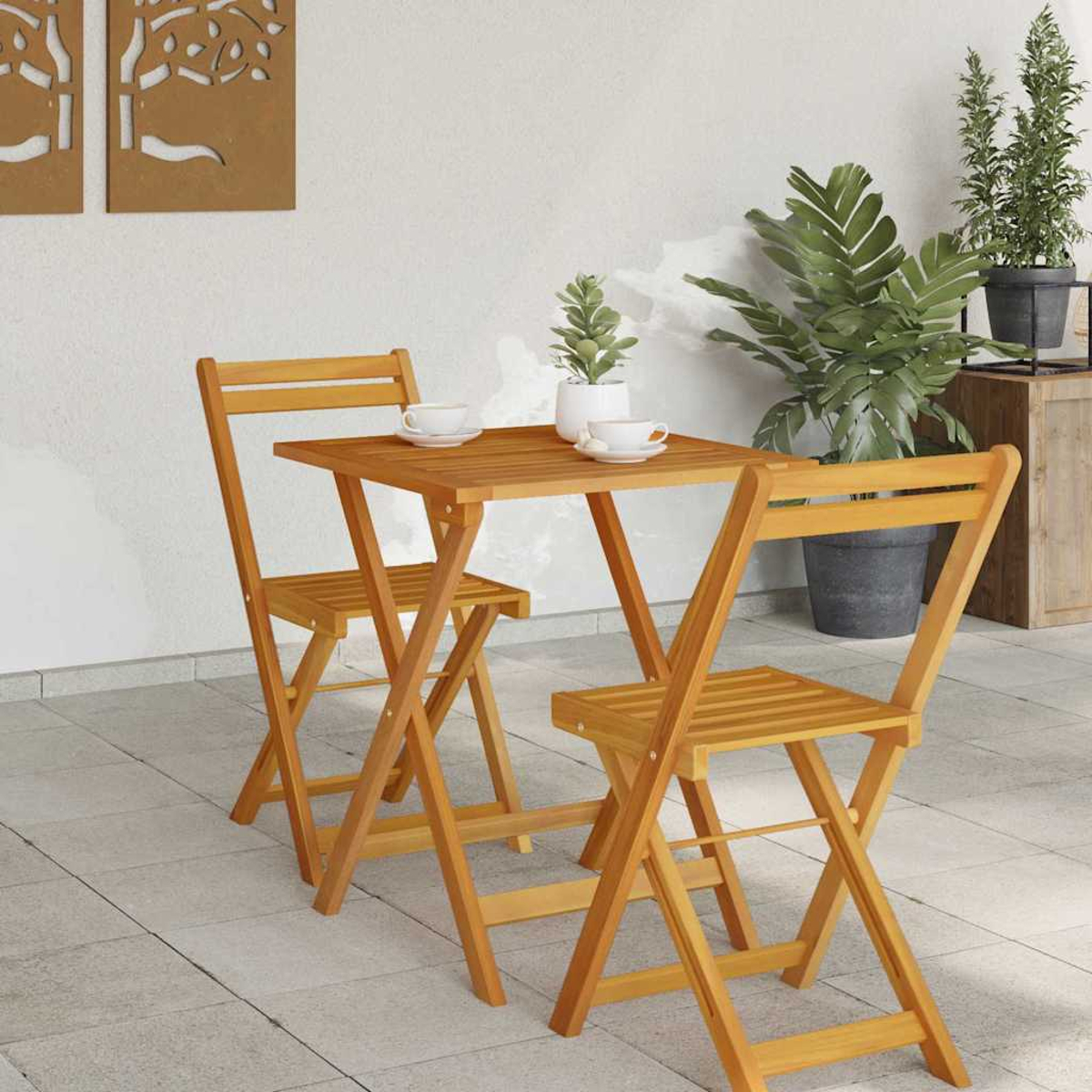 Holz-Bistro-Set mit zwei Stühlen und einem quadratischen Tisch auf einer gefliesten Terrasse, mit Pflanzen im Hintergrund und zwei Tassen auf dem Tisch.