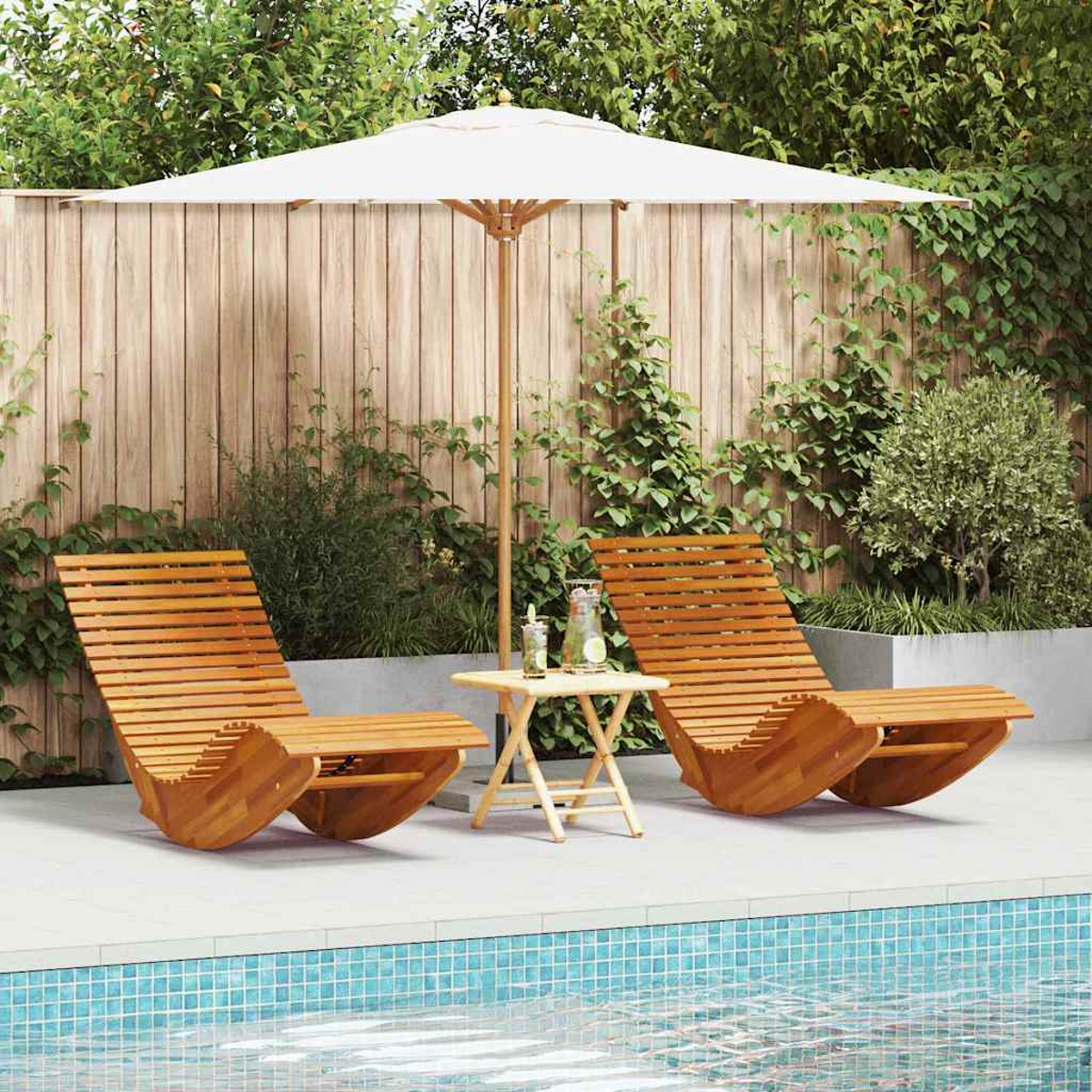 Zwei Holzliegen und ein kleiner Tisch unter einem weißen Sonnenschirm am Pool, dahinter ein Holzzaun und Grün.