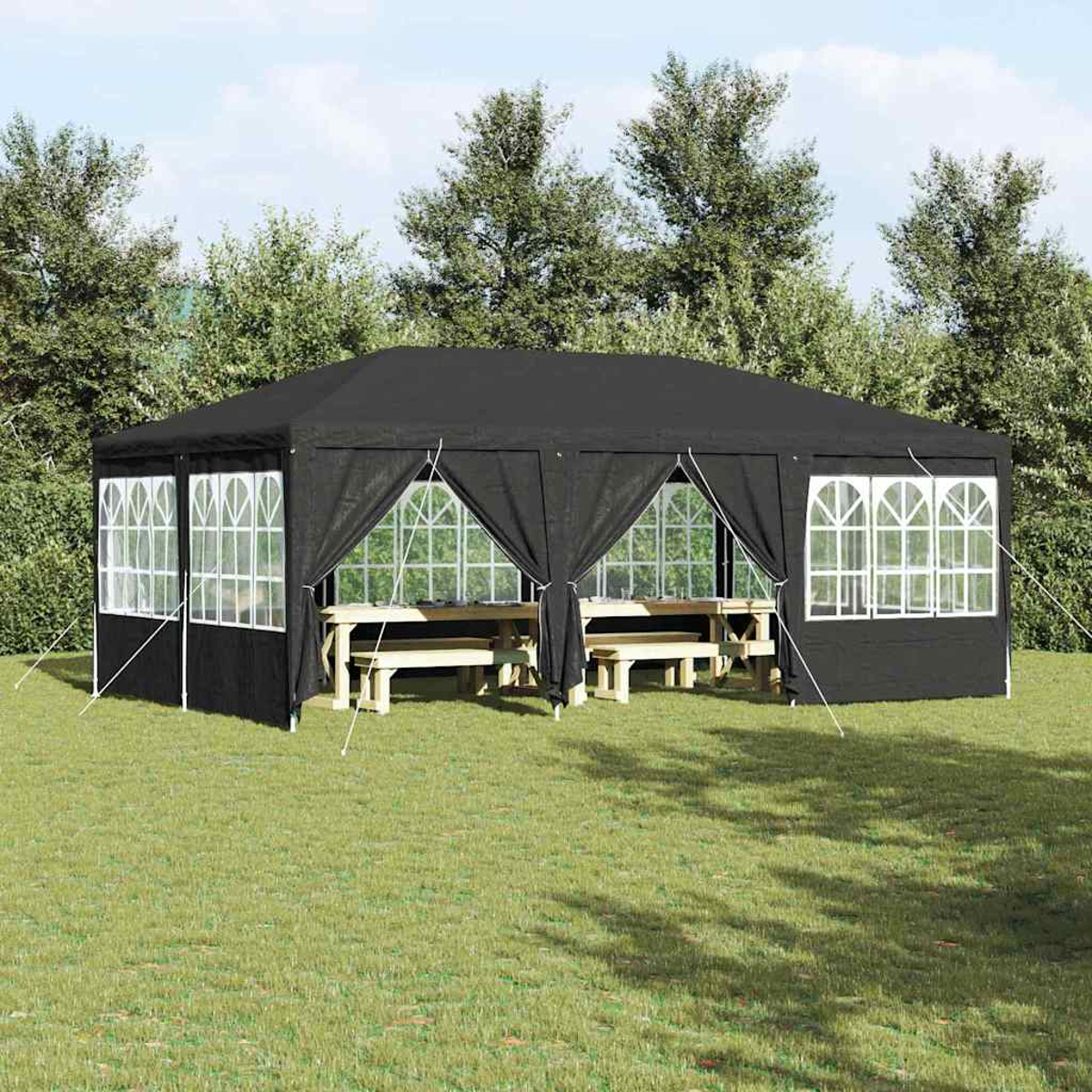 Un gazebo nero con finestre con cornice bianca è sull'erba. All'interno ci sono tavoli da picnic. Gli alberi formano lo sfondo e il cielo è visibile.