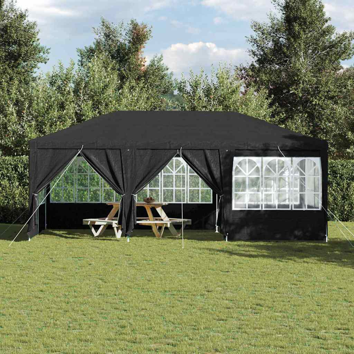 Un gazebo nero con finestre e un tavolo da picnic all'interno è sull'erba verde. Gli alberi formano lo sfondo sotto un cielo blu.