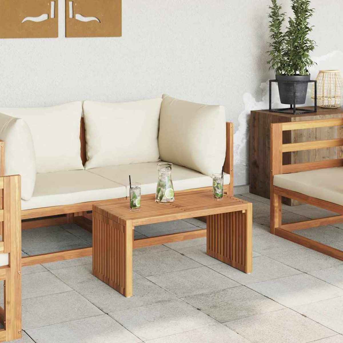 Terrasse mit hellen Holzmöbeln. Gepolstertes Sofa, Tisch mit Getränken, Topfpflanze und Stuhl sind sichtbar. Beige Kissen.
