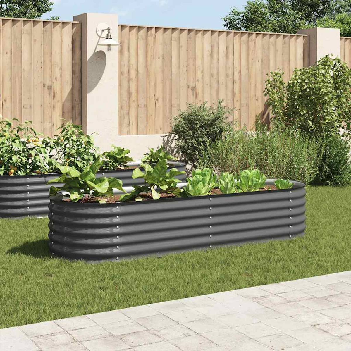 Gemüsegarten mit grauen Metallpflanzgefäßen mit Pflanzen auf grünem Gras. Im Hintergrund ein Holzzaun und Büsche.
