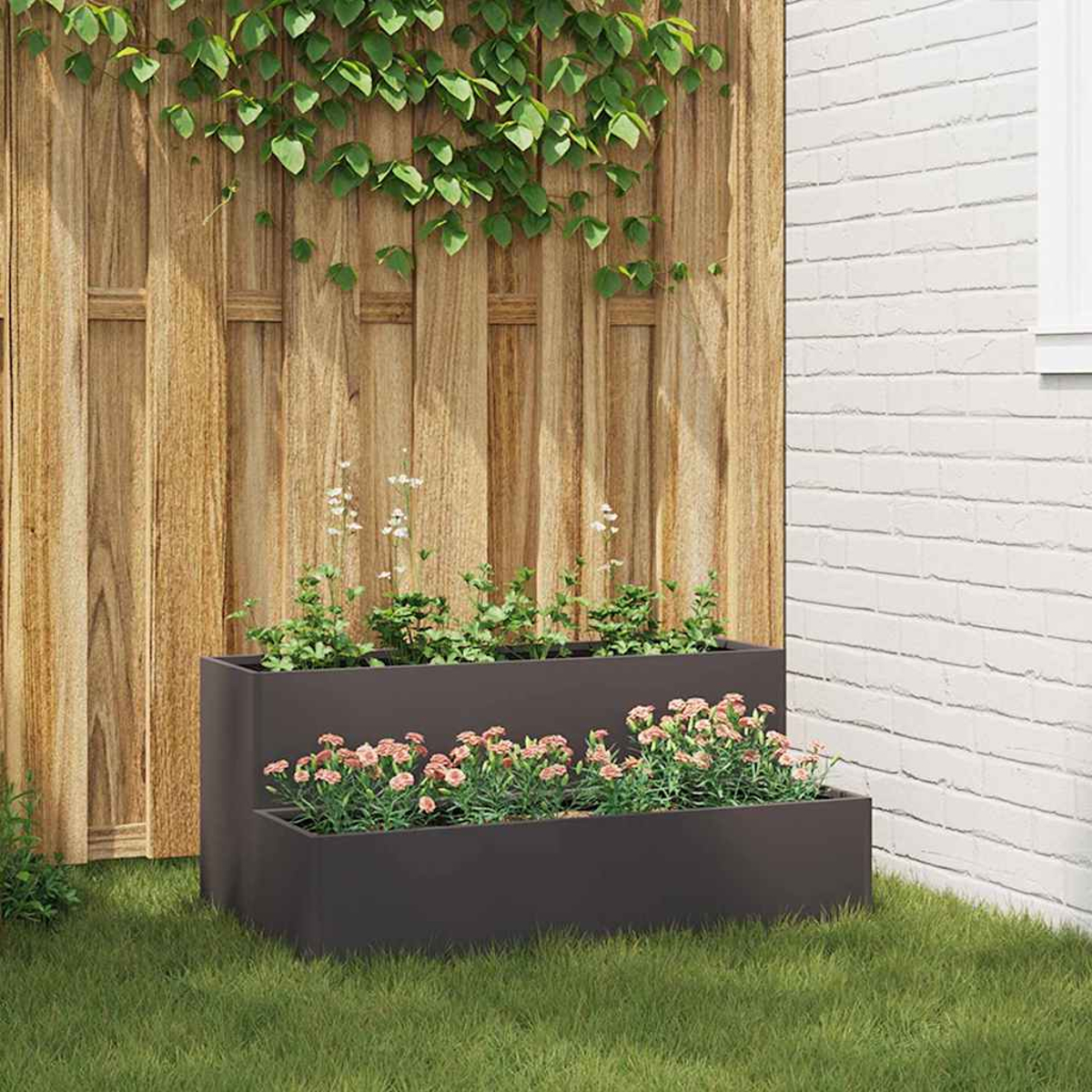Una fioriera a due livelli con fiori rosa è posizionata sull'erba. Una recinzione di legno e un muro di mattoni bianchi fanno da sfondo, con viti.