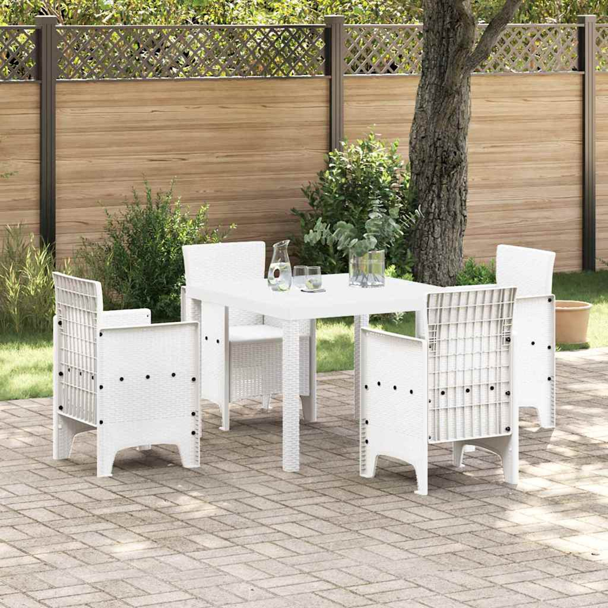 Ein weißer Tisch mit vier Stühlen in einem Garten. Im Hintergrund steht ein Baum. Ein Holzzaun ist sichtbar.