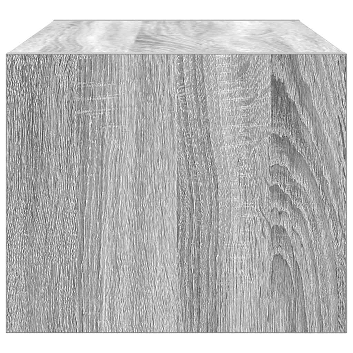 Gezeigt wird ein grauer Holzblock. Die Holzmaserung ist sichtbar. Der Block hat eine quadratische Form und liegt auf einer weißen Oberfläche.