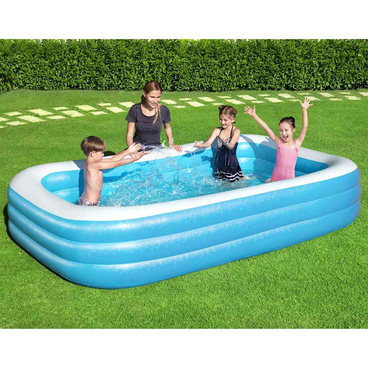 Vier Kinder und ein Erwachsener planschen in einem blauen Planschbecken auf Gras. Sie spritzen mit Wasser und haben Spaß.