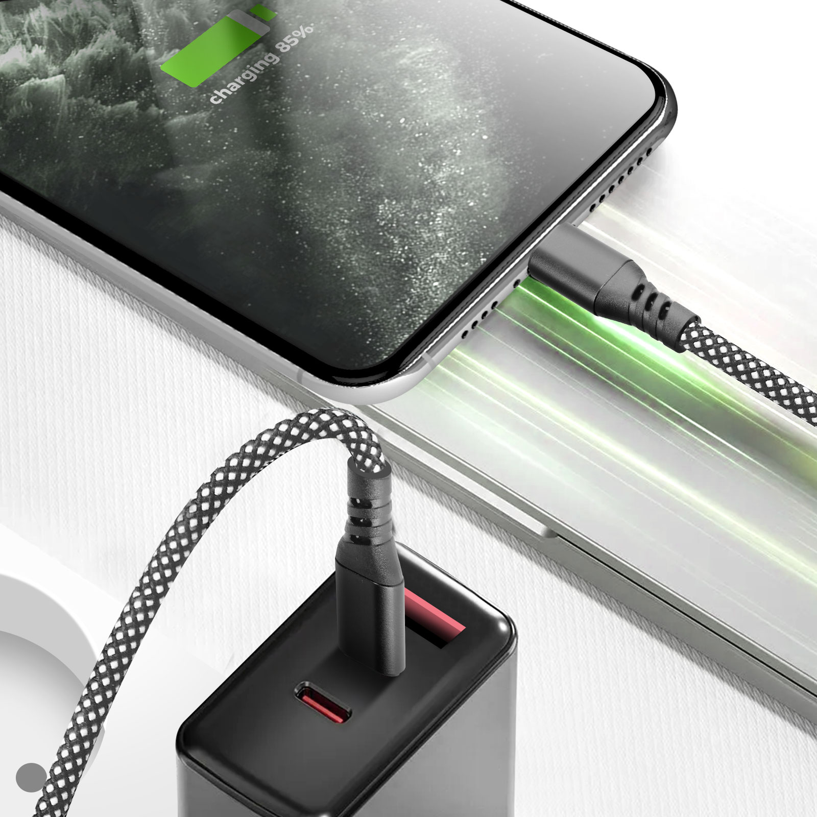 Un smartphone se charge avec un câble noir et blanc. Le téléphone affiche 85% de charge. Un chargeur noir est connecté.