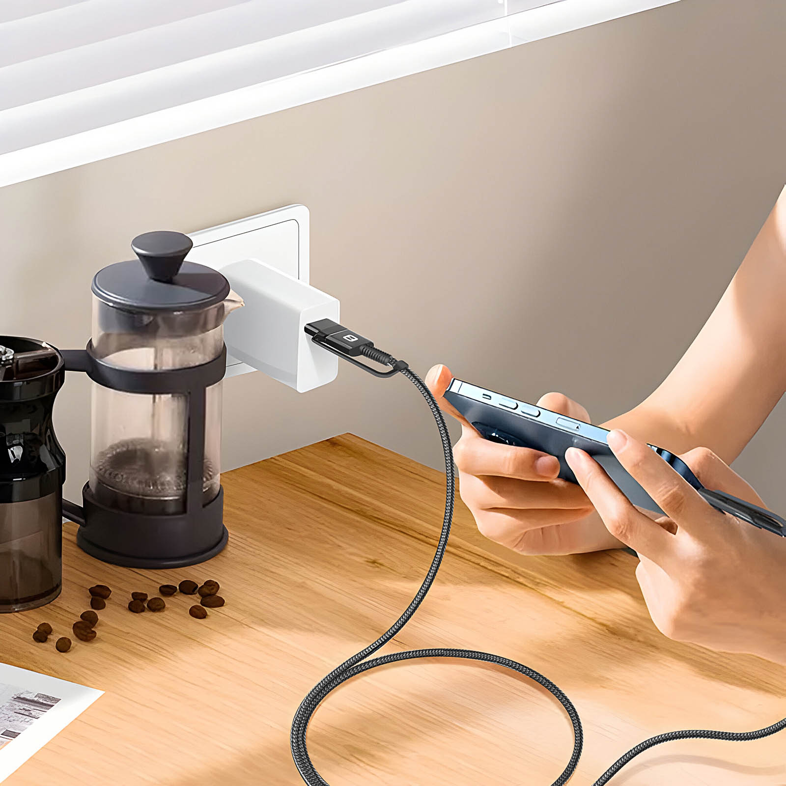 Un telefono è in carica. Nella foto sono presenti anche una caffettiera, chicchi di caffè e un adattatore di alimentazione.