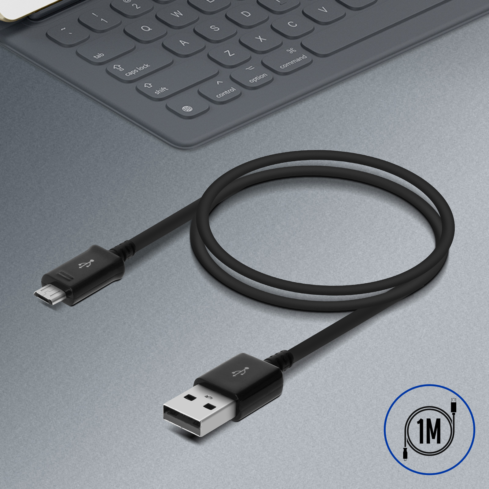 Un cavo USB nero con connettore USB-A e micro-USB, su una superficie grigia. Una tastiera è visibile sullo sfondo.