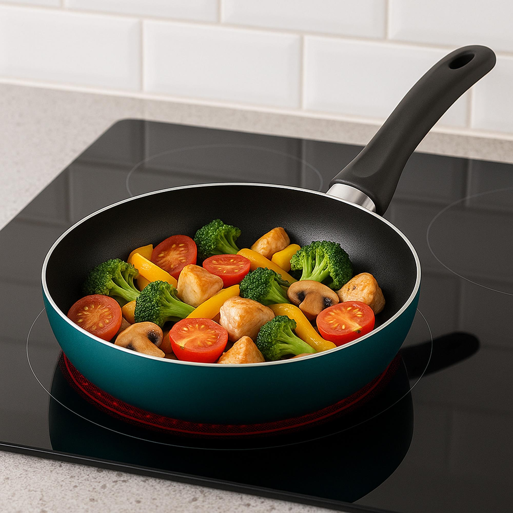 Una sartén turquesa sobre una estufa negra contiene verduras cocidas: tomates, brócoli, pimientos amarillos, champiñones y pollo.