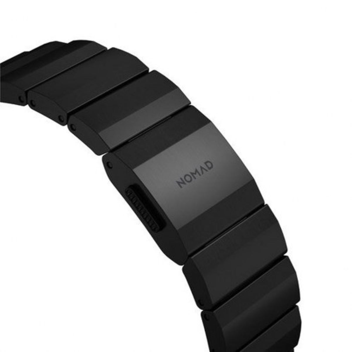 Primer plano de una correa de reloj negra. La palabra 'NOMAD' es visible. La correa está hecha de eslabones rectangulares conectados.