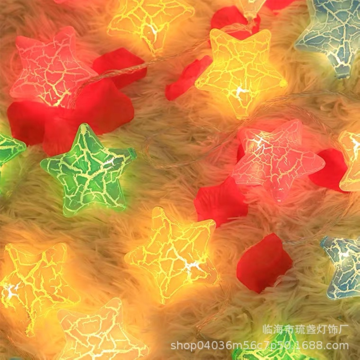 Lichterketten mit bunten sternförmigen Lichtern. Rote Blütenblätter sind verstreut. Der Hintergrund ist eine flauschige Oberfläche.