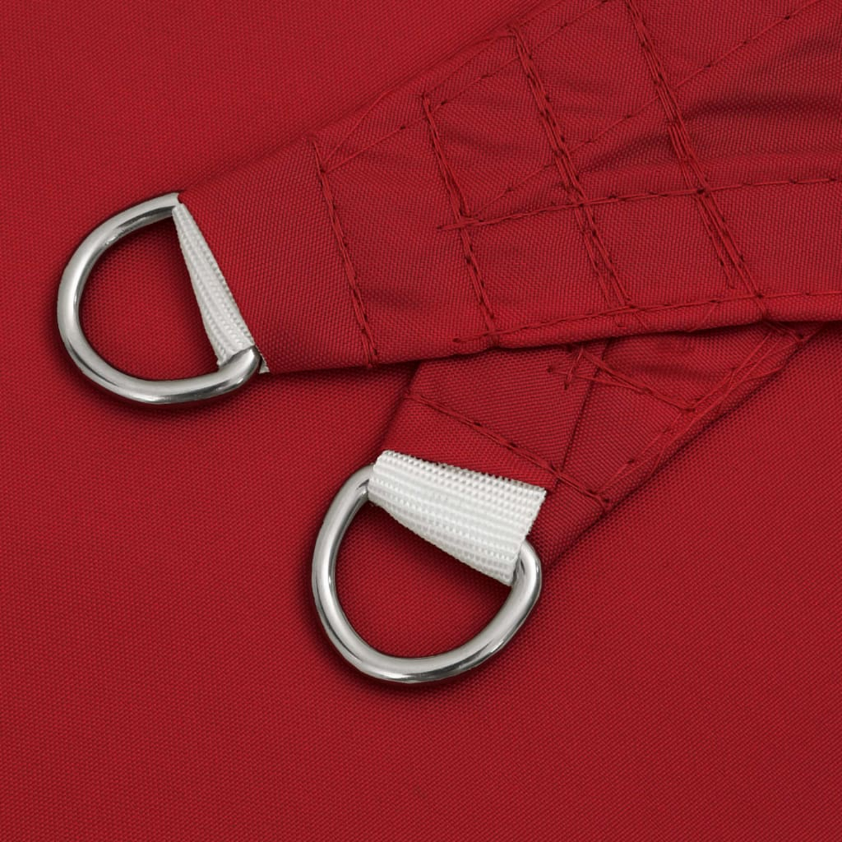 Nahaufnahme eines roten Sonnensegels mit zwei silbernen D-Ringen, die mit weißem Stoff befestigt sind. Der Stoff ist in einem Rastermuster vernäht.