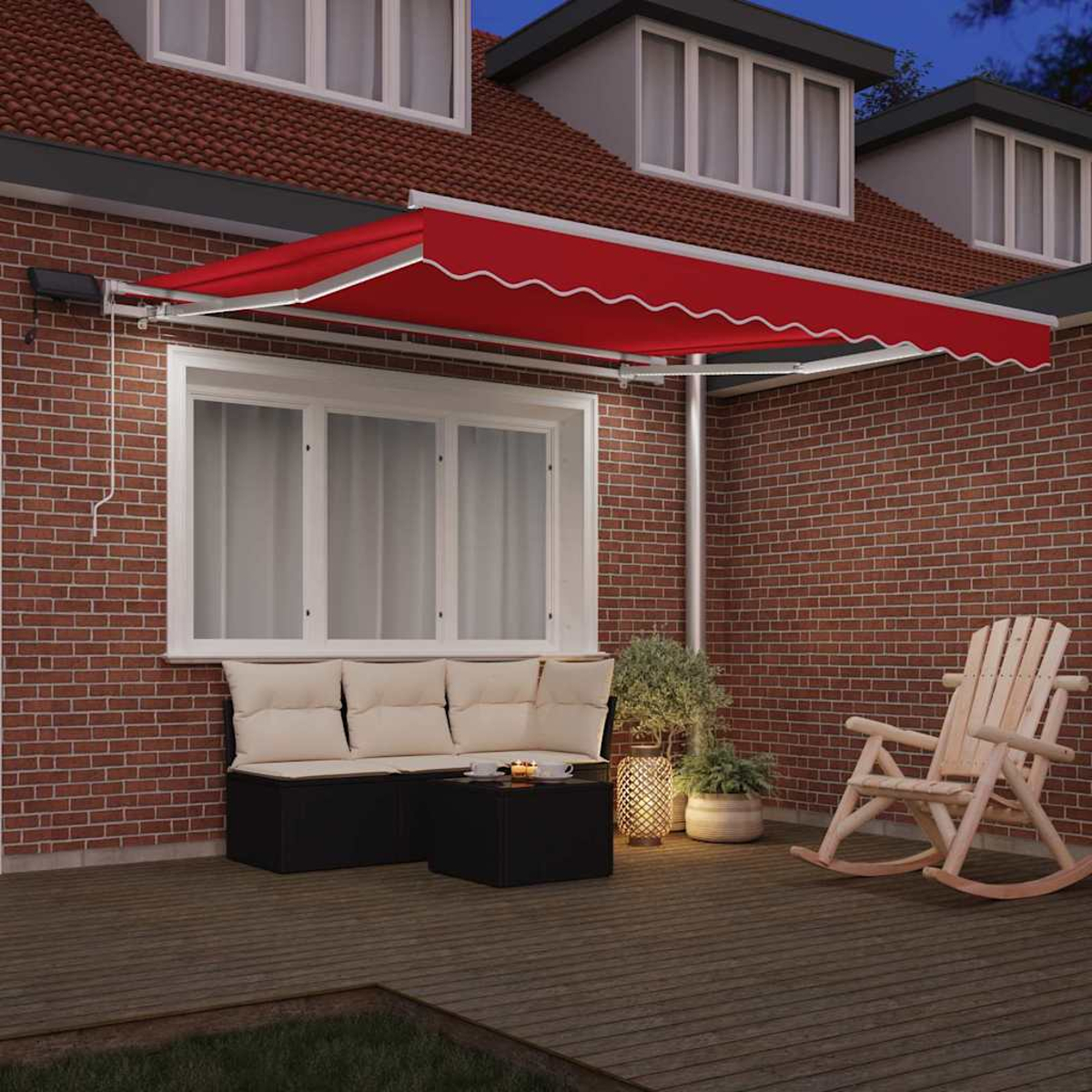 Eine rote Markise bedeckt eine Terrasse. Ein hölzerner Schaukelstuhl und ein schwarzer Tisch befinden sich vor einer Ziegelmauer. Ein Sofa mit cremefarbenen Kissen ist sichtbar.