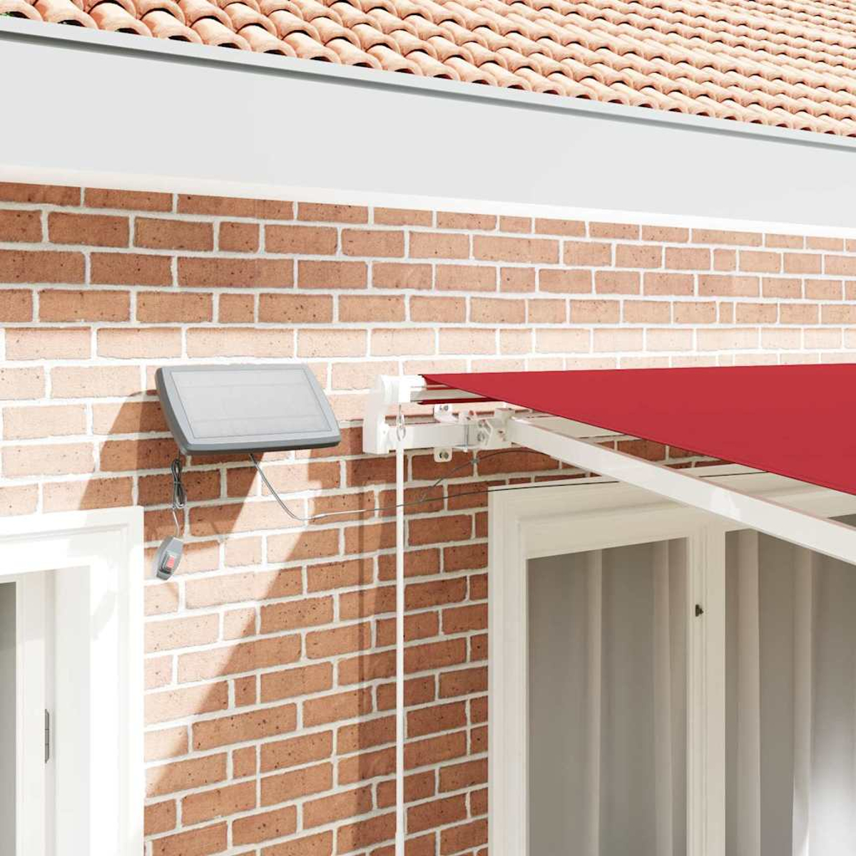Ein rotes Sonnensegel erstreckt sich von einer Backsteinmauer neben einem weißen Fenster. Ein Solarpanel und eine Fernbedienung sind befestigt.