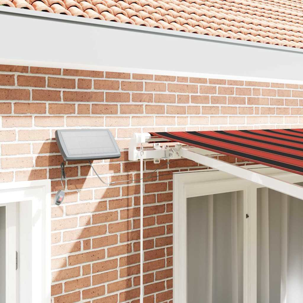 Eine Ziegelmauer mit einer rot-schwarz gestreiften Markise. Ein graues Solarpanel ist an der Wand befestigt. Rotes Ziegeldach im Hintergrund.