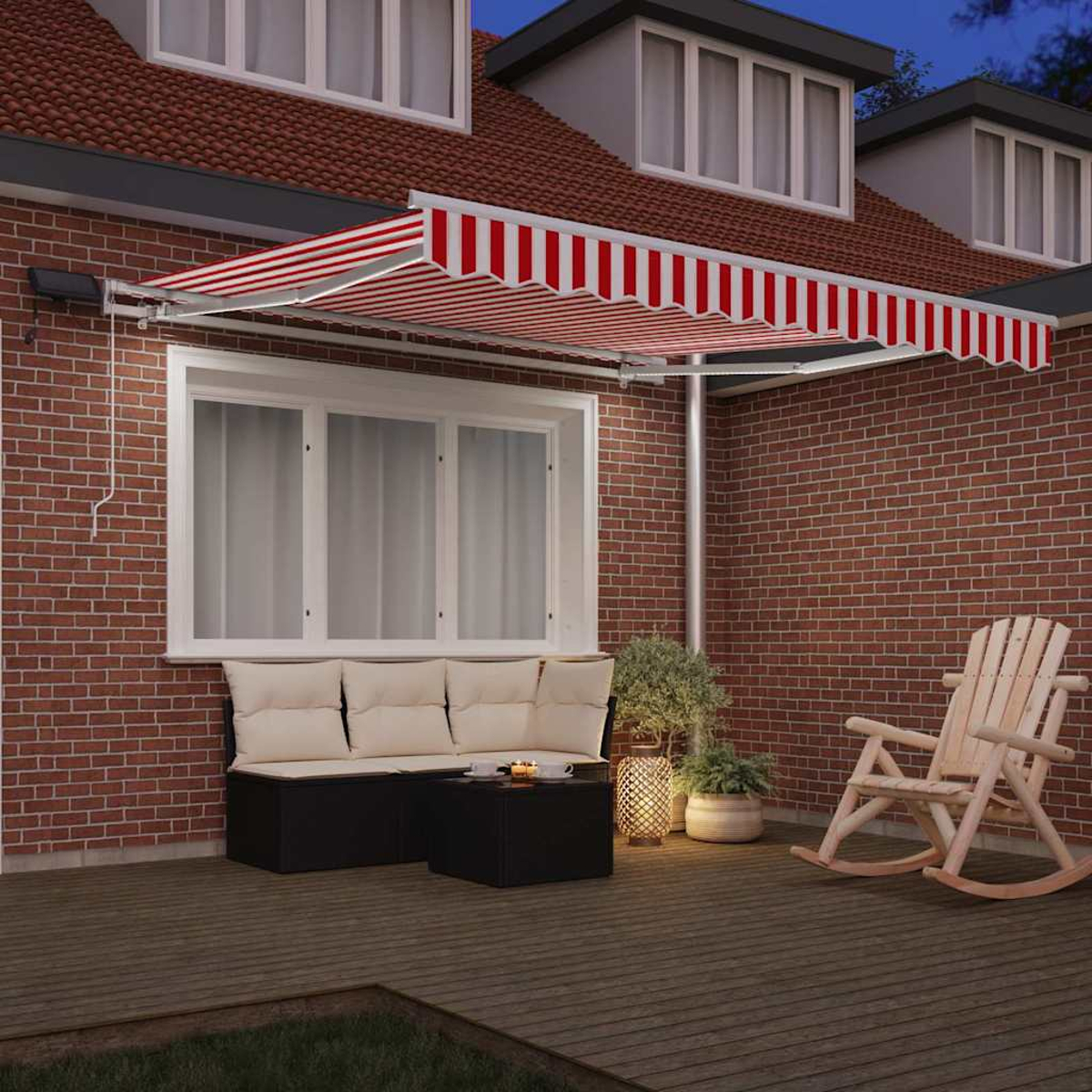 Ein rot-weiß gestreifter Sonnenschirm bedeckt eine Außenterrasse. Eine Bank, ein Tisch und ein Schaukelstuhl stehen auf der Holzterrasse.