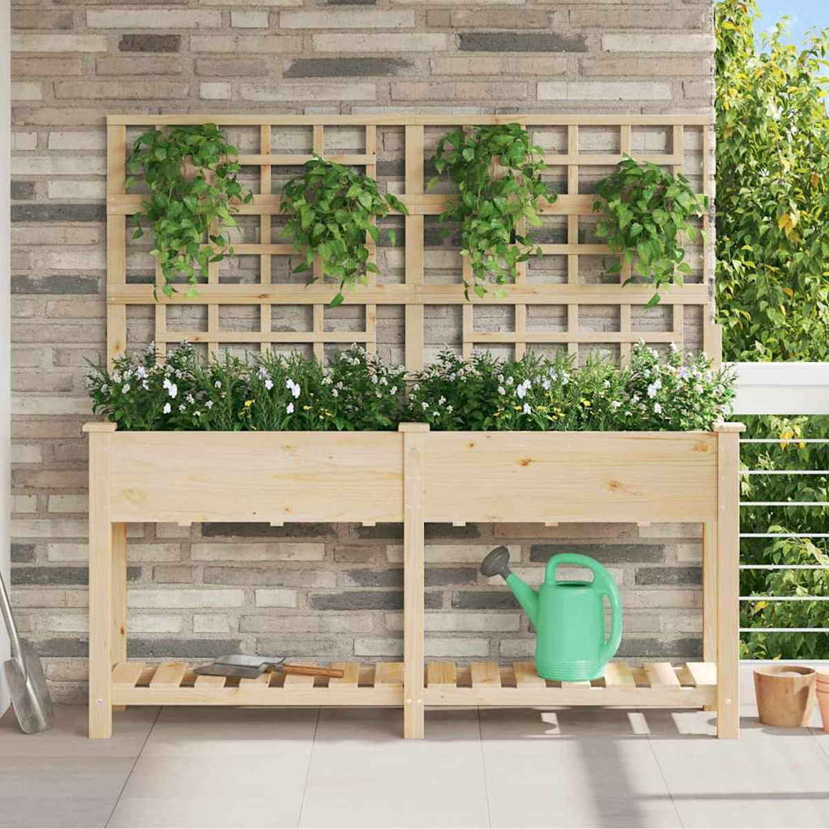 Fioriera in legno con piante e traliccio. Annaffiatoio verde sotto. Parete in mattoni, balcone con verde.
