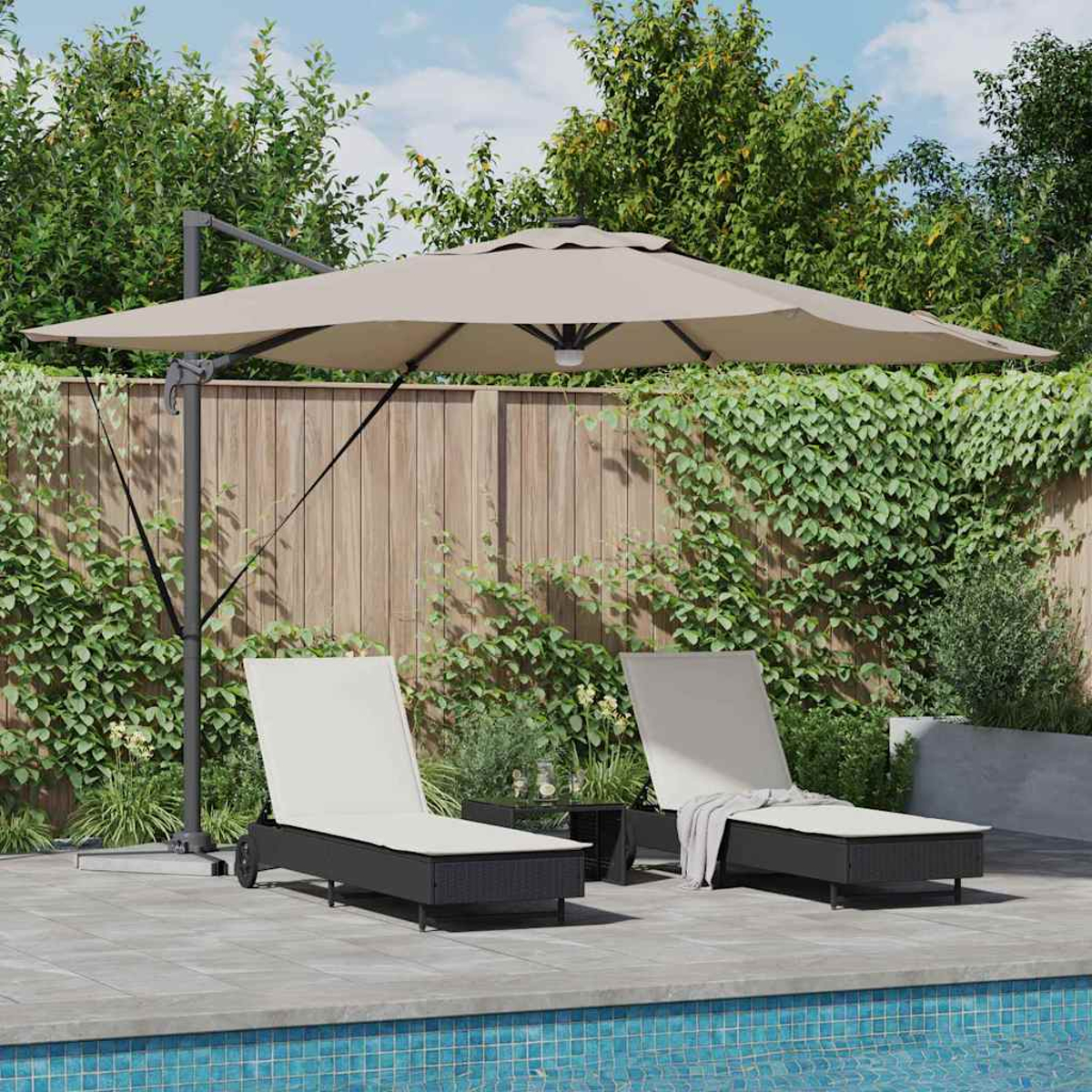 Due sedie a sdraio sotto un ombrellone beige vicino a una piscina. Recinzione di legno e fogliame verde sullo sfondo. Ambiente esterno soleggiato.