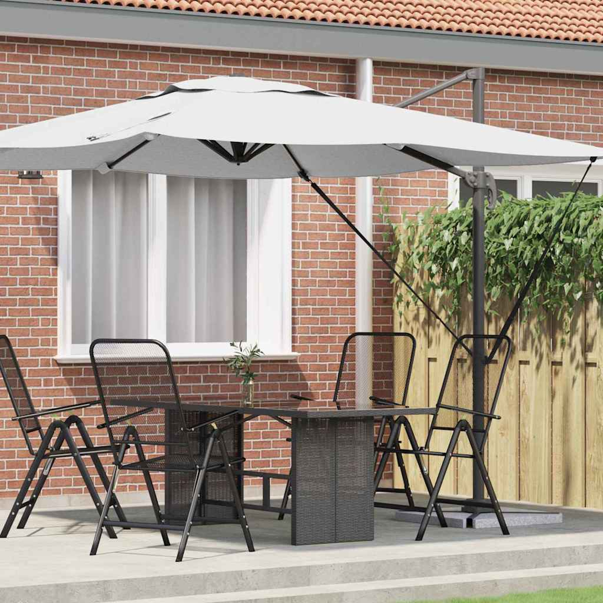 Szene im Freien mit Tisch, Stühlen und einem weißen Sonnenschirm. Eine Ziegelmauer und ein Holzzaun bilden den Hintergrund.