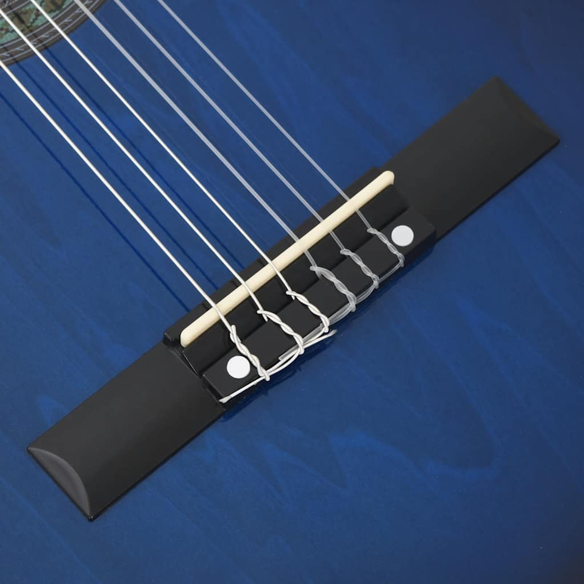 Nahaufnahme einer blauen Gitarre. Weiße Saiten verlaufen über einen schwarzen Steg. Der Gitarrenkörper hat eine blaue Holzmaserung.
