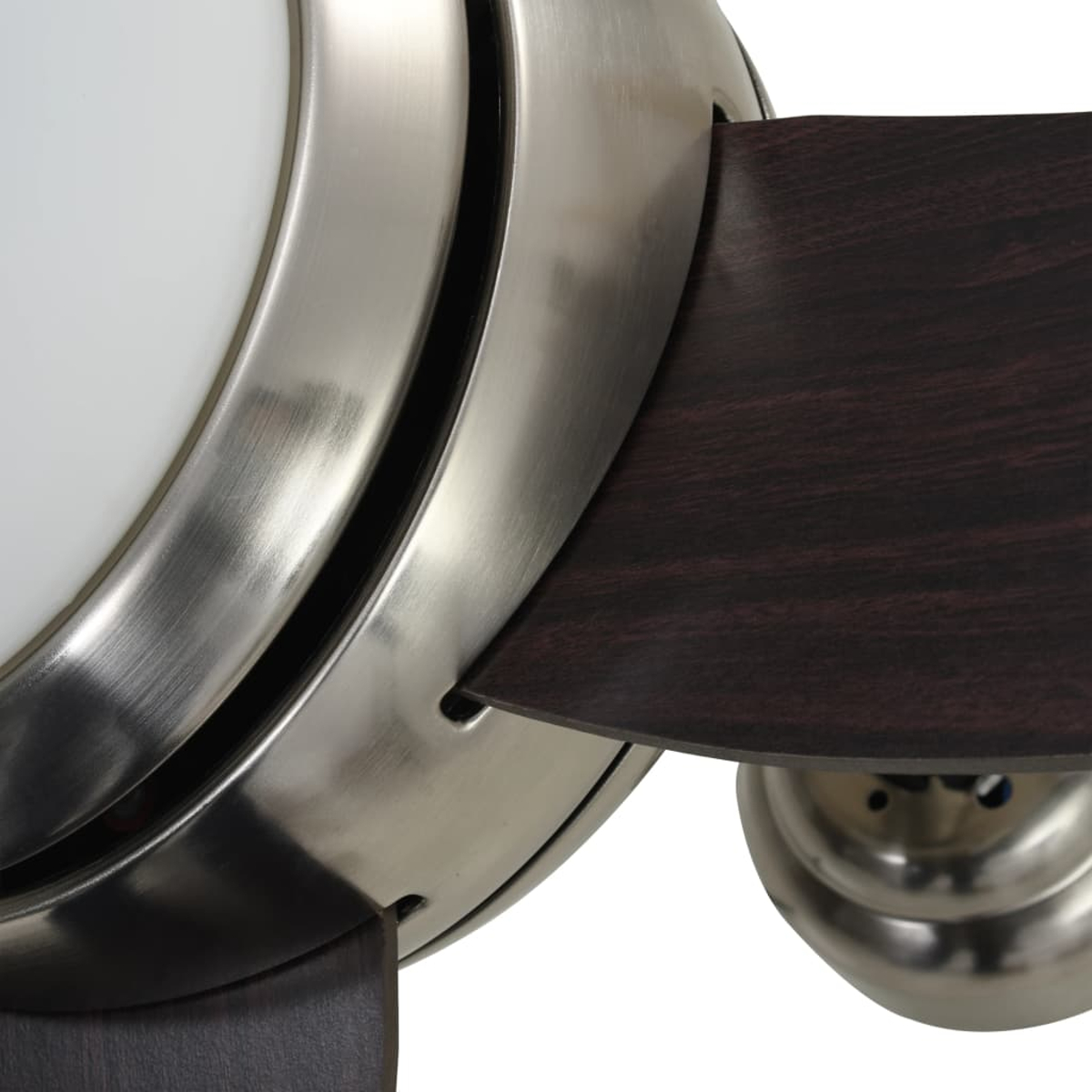 Primo piano di un ventilatore da soffitto. Ha un alloggiamento metallico, una luce bianca e una pala in legno scuro. Il ventilatore è su sfondo bianco.