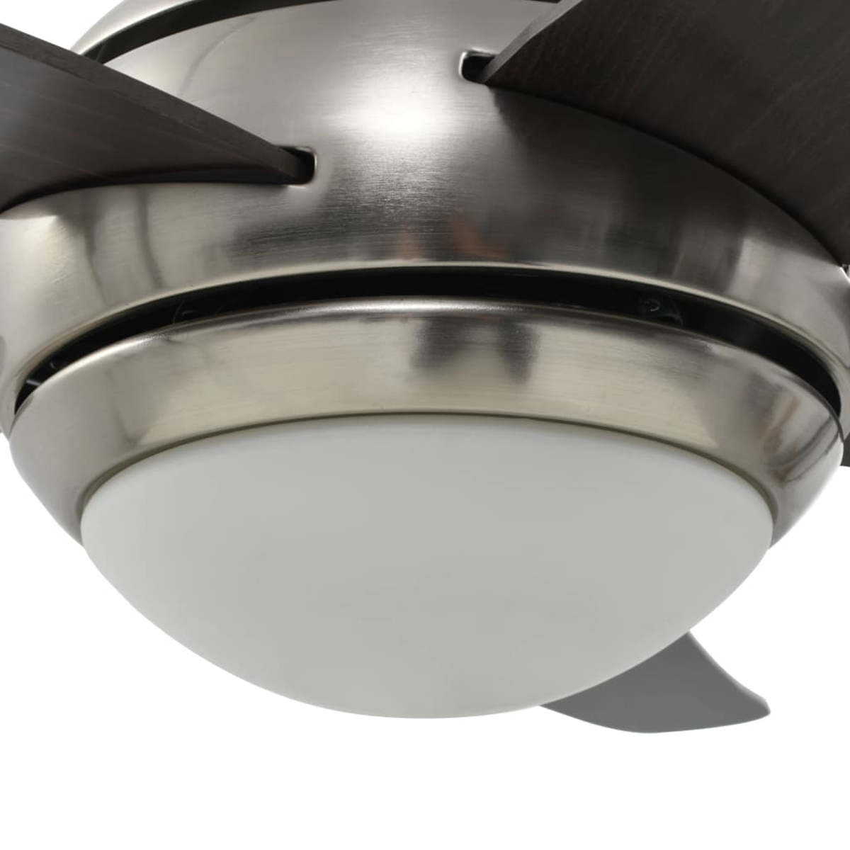 Primo piano di un ventilatore da soffitto. Ha una base argentata e pale marrone scuro. La luce è bianca.