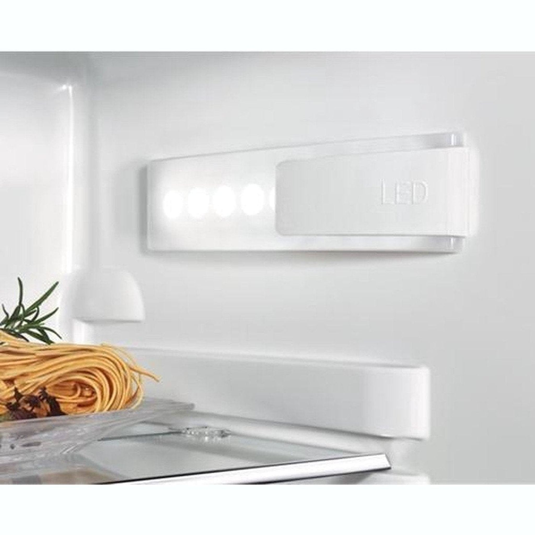 In een koelkast: LED-verlichting, pasta en rozemarijn. Het licht is aan. Wit interieur.