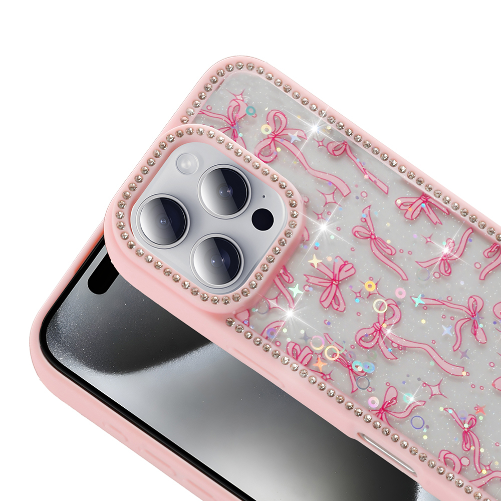 Pembe telefon kılıfı, kurdeleler ve yapay elmaslarla süslü. Telefonun kamerası görünür durumda. Şeffaf kapakta ışıltılı efekt.