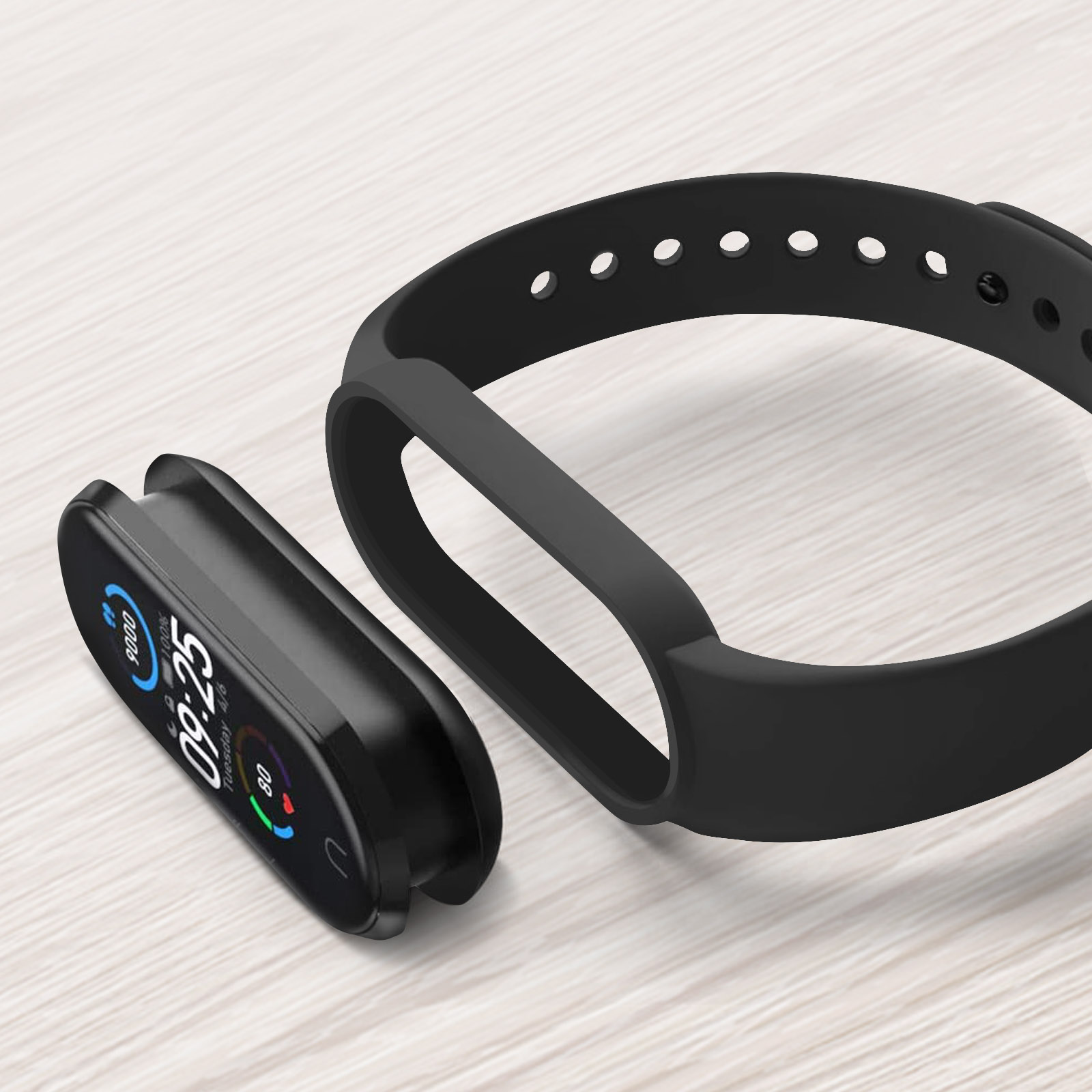 Smartwatch e cinturino neri su una superficie in legno chiaro. L'orologio mostra ora e statistiche. Cinturino staccato.