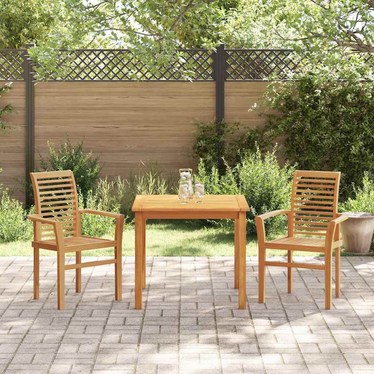 Holz-Terrassenset: Tisch und zwei Stühle. Hinterhof mit Holzzaun, üppigem Grün und Ziegelpflaster. Zwei Gläser auf dem Tisch.