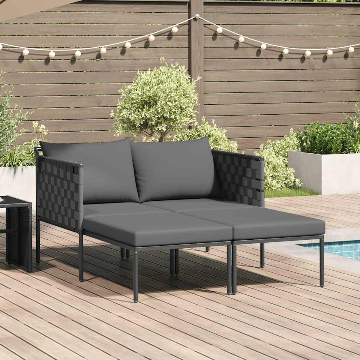 Graues Outdoor-Sofa auf einer Holzterrasse. Es hat zwei Kissen und eine gewebte Rückenlehne. Im Hintergrund sind ein Holzzaun und Pflanzen.