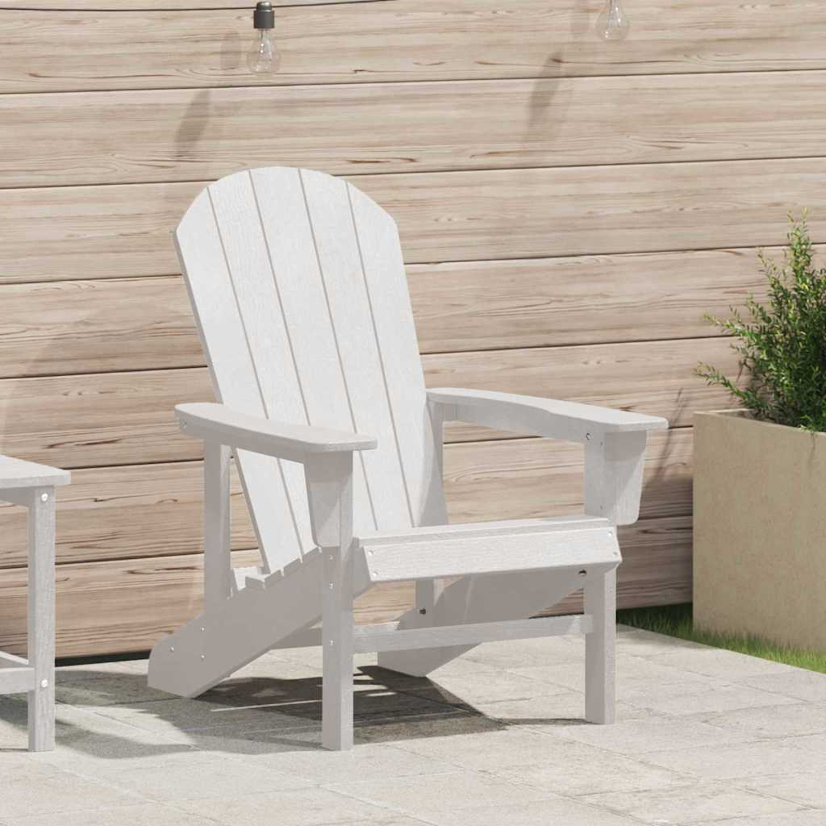 Silla Adirondack blanca en un patio. Valla de madera al fondo. Una planta en maceta a la derecha. Bombillas colgando arriba.