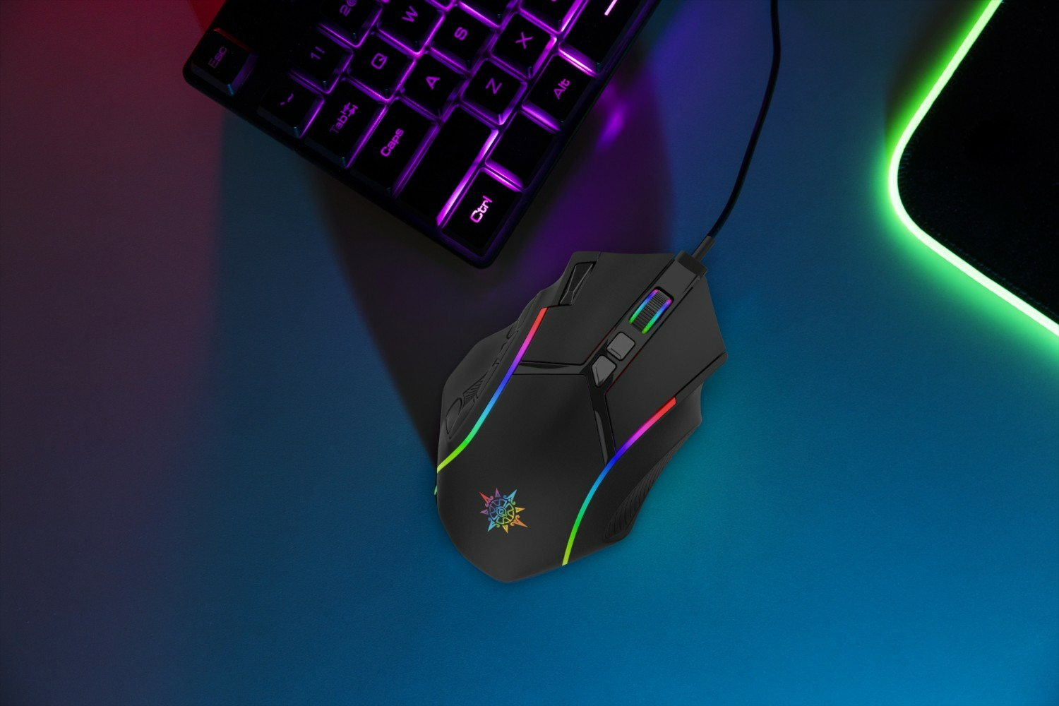 A black gaming mouse with colorful LED lights sits on a blue surface next to a keyboard. The keyboard and mousepad are also visible.