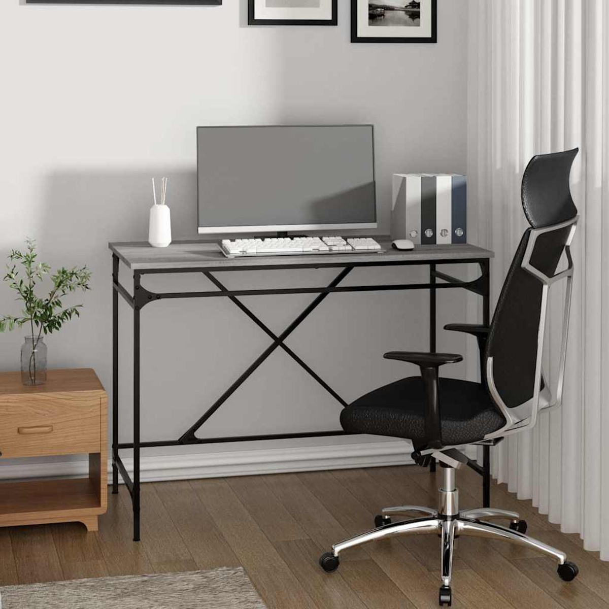 Ein Homeoffice mit Schreibtisch, Computer, Bürostuhl und Holz-Beistelltisch. Die Wand hat Bilder und weiße Vorhänge.