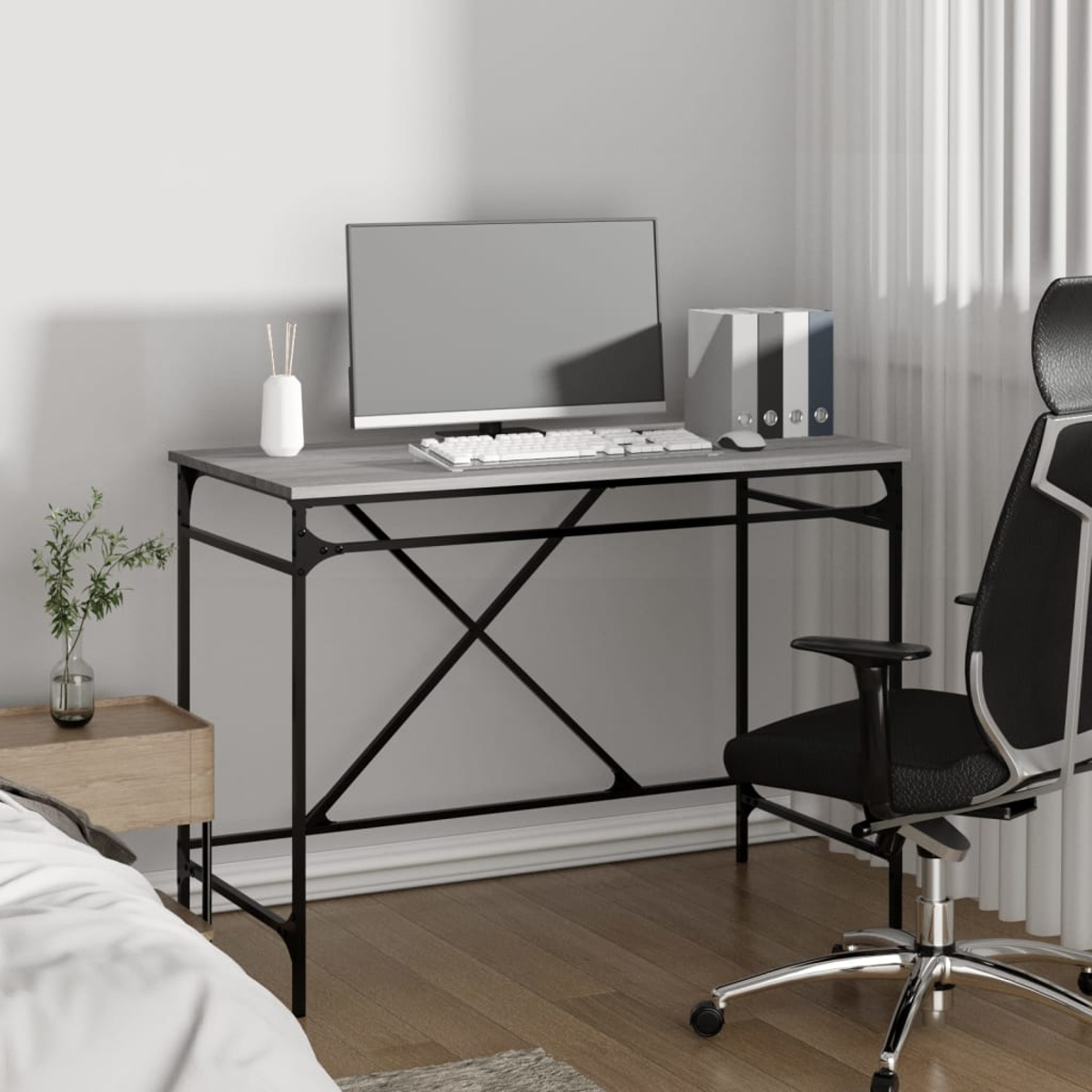 Eine Heimbüroszene mit Schreibtisch, Computer, Stuhl und Fenster. Der Schreibtisch hat eine graue Platte und schwarze Beine. Es gibt ein Bett.