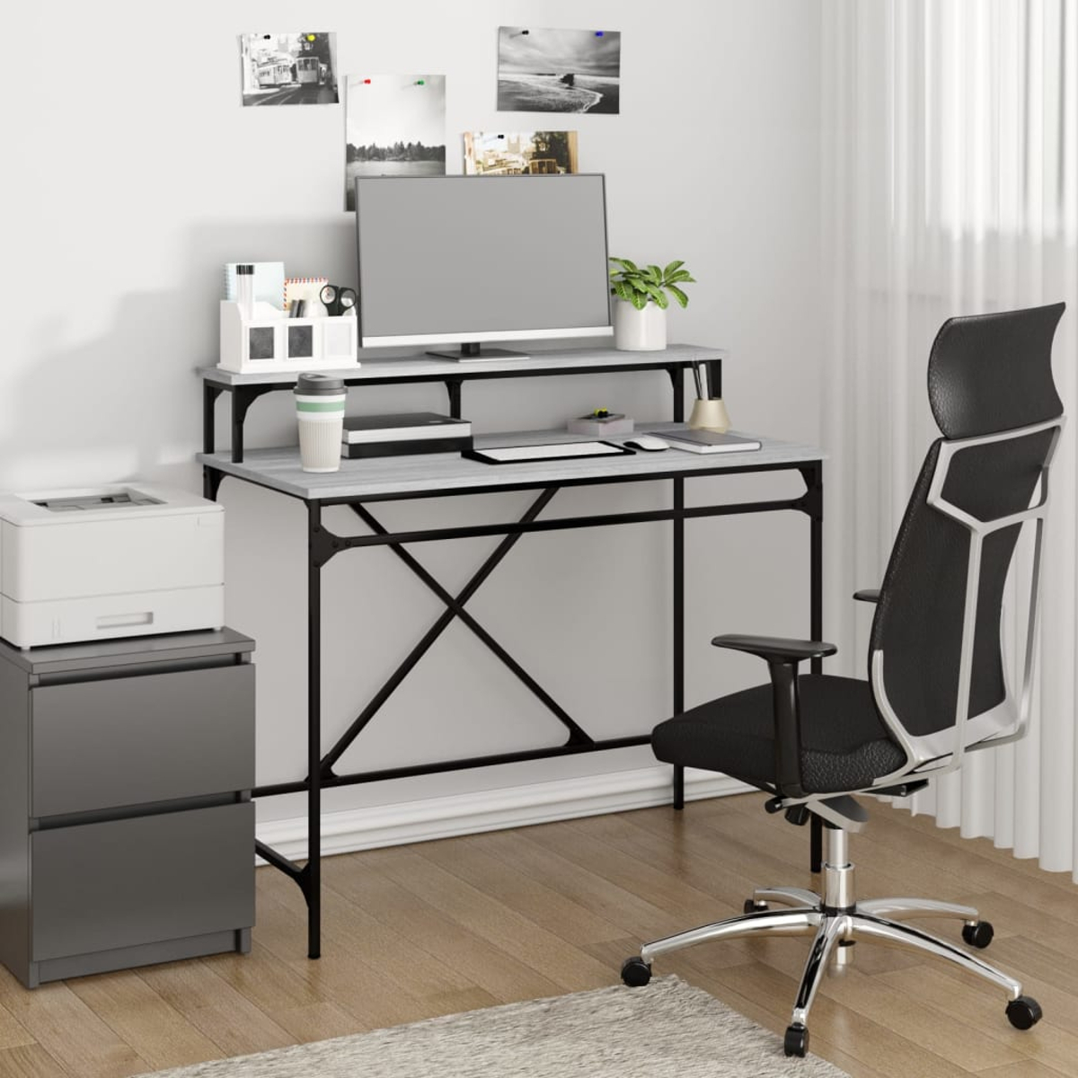 Büroausstattung mit Schreibtisch, Computer, Stuhl und Drucker. Weiße Wand, Fenster mit transparenten Vorhängen und Bildern.