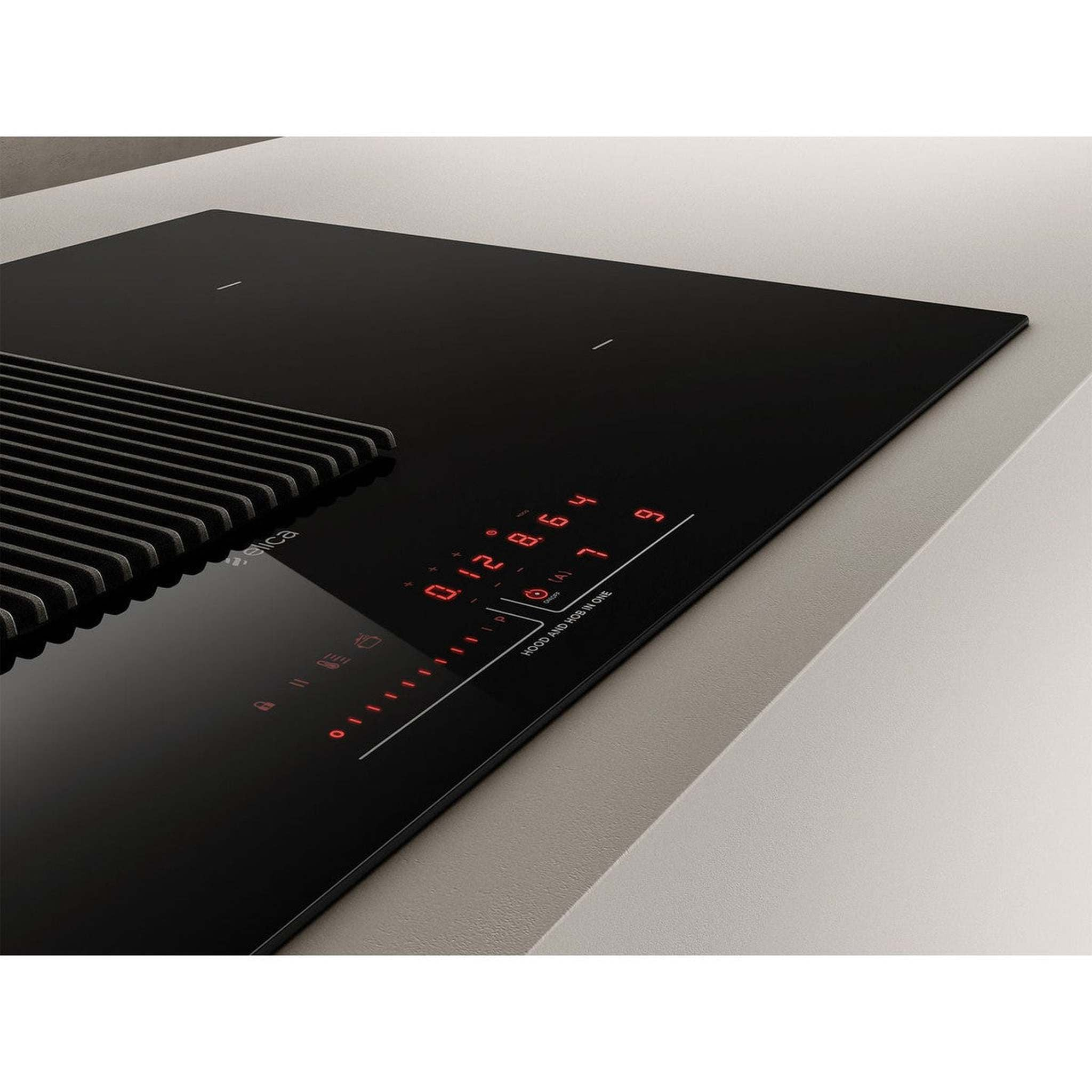 Una placa de inducción negra con pantalla digital roja. Tiene un extractor integrado y está sobre una encimera clara.