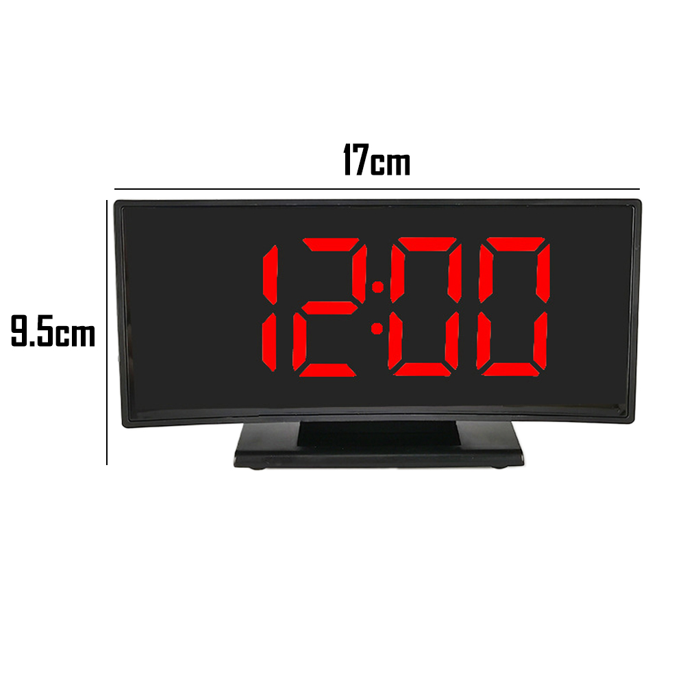 Eine Digitaluhr, die 12:00 in Rot auf schwarzem Bildschirm anzeigt. Abmessungen sind 17 cm breit und 9,5 cm hoch. Sie steht auf einem schwarzen Sockel.