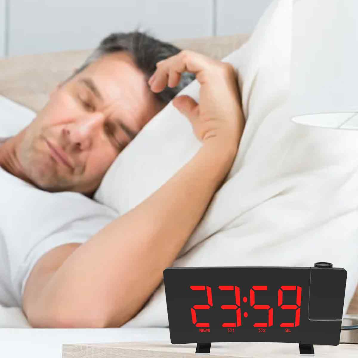 Ein Mann schläft im Bett neben einem Wecker, der 23:59 anzeigt. Er liegt an einem weißen Kissen. Die Uhr ist schwarz.