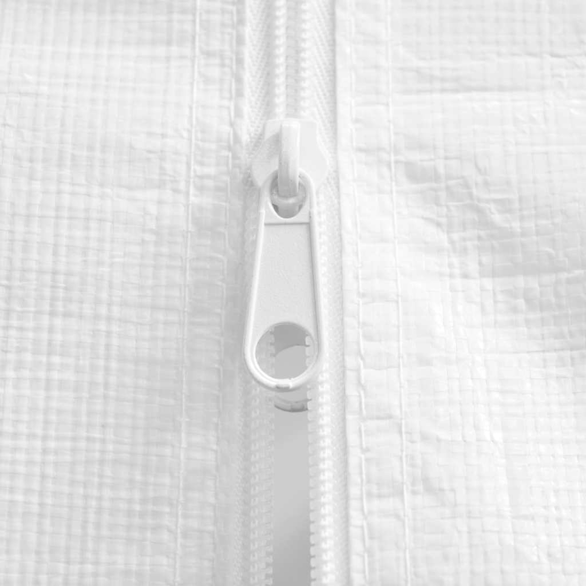 Primer plano de una cremallera blanca sobre tela blanca texturizada. La cremallera está centrada y abierta.