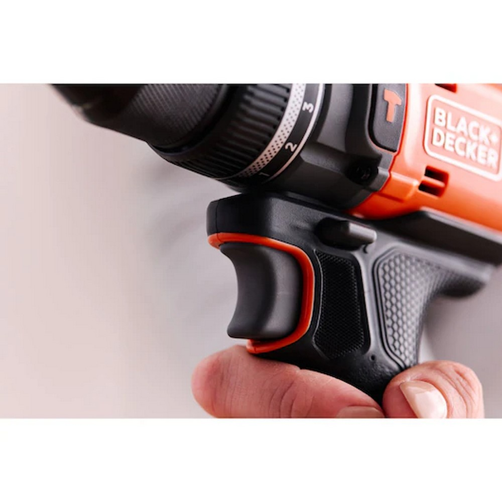 Siyah ve turuncu bir Black+Decker matkabını tutan bir el. Matkap odak noktasında, el tutacağı kavrıyor.