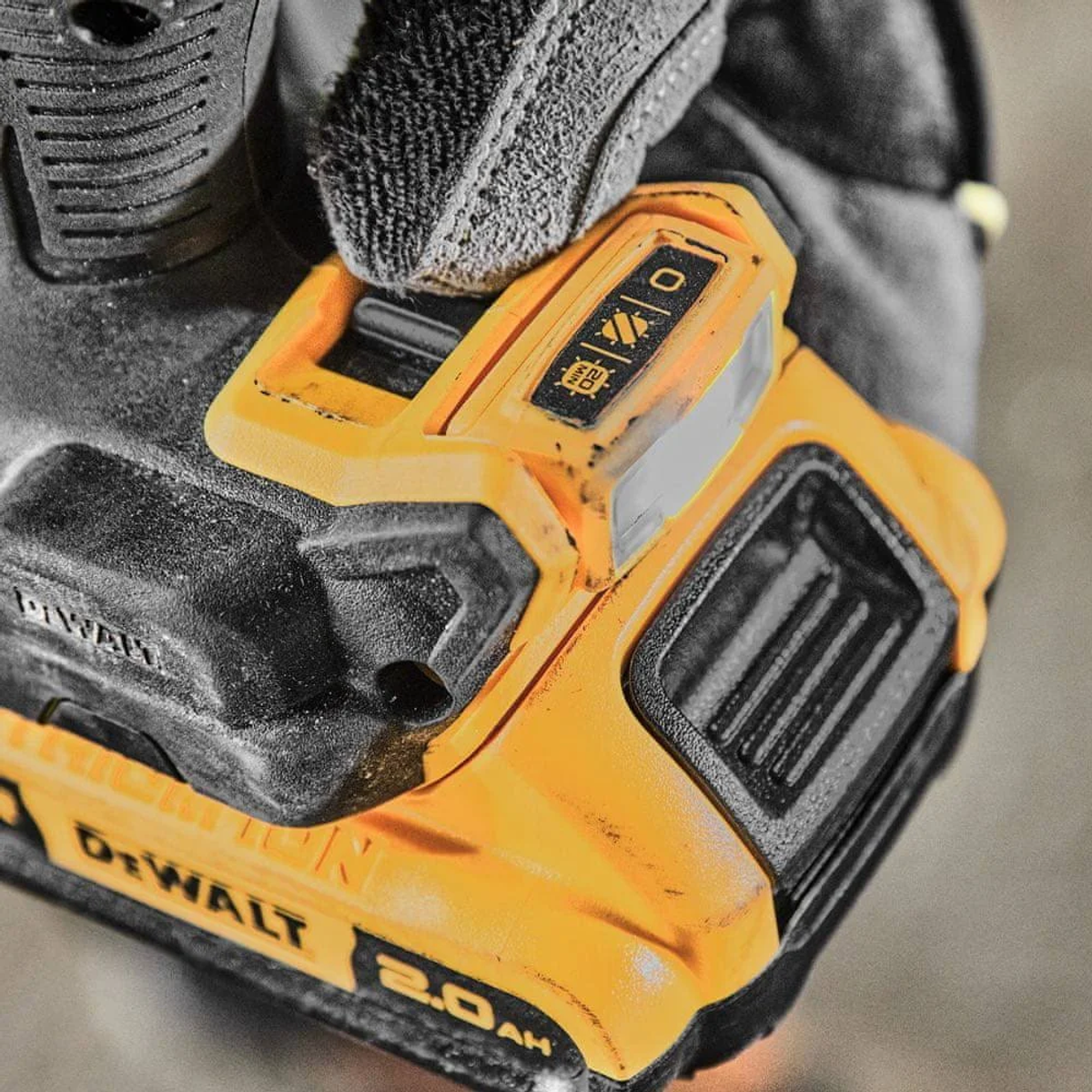 Zbliżenie żółto-czarnej baterii DeWalt 2.0Ah trzymanej w rękawicy. Bateria ma różne symbole i szczegóły.
