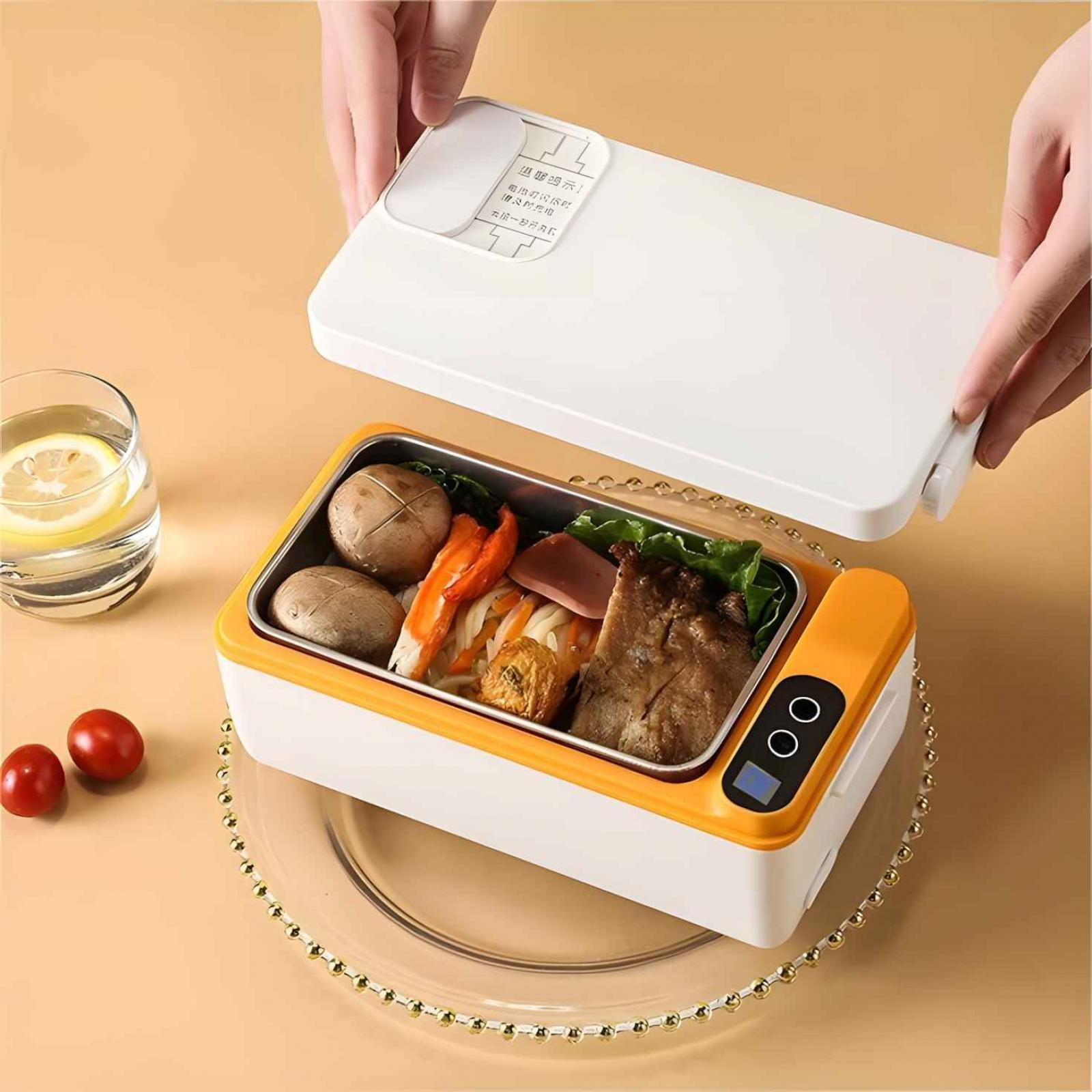 Hände öffnen eine Lunchbox mit Essen. Ein Glas Wasser mit Zitrone, Tomaten und ein dekorativer Teller sind sichtbar.