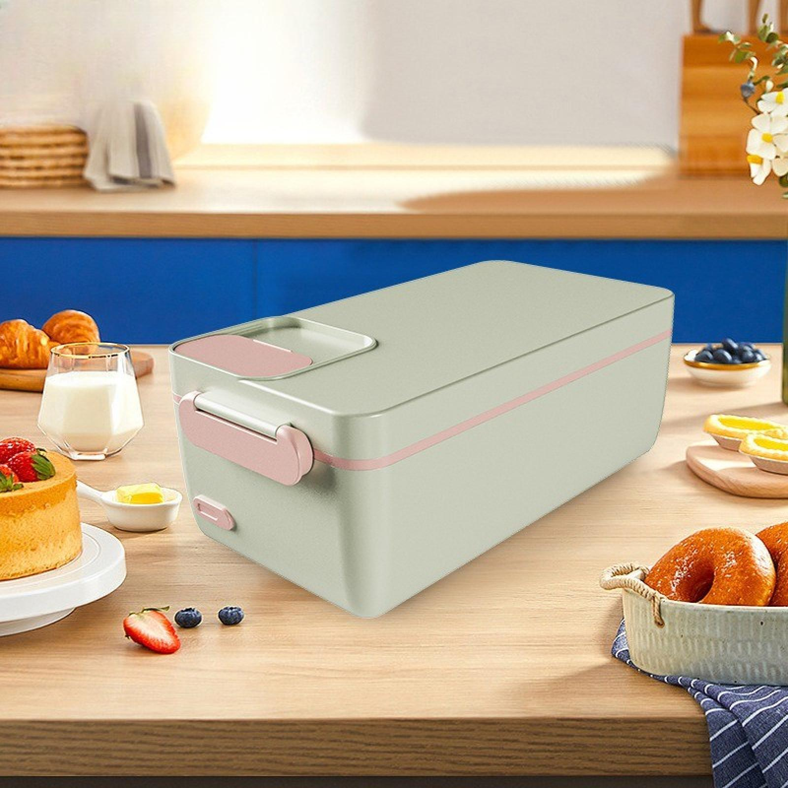 Eine Lunchbox mit Croissants, Kuchen, Obst und Milch auf einem Holztisch. Im Hintergrund eine Küchenzeile.