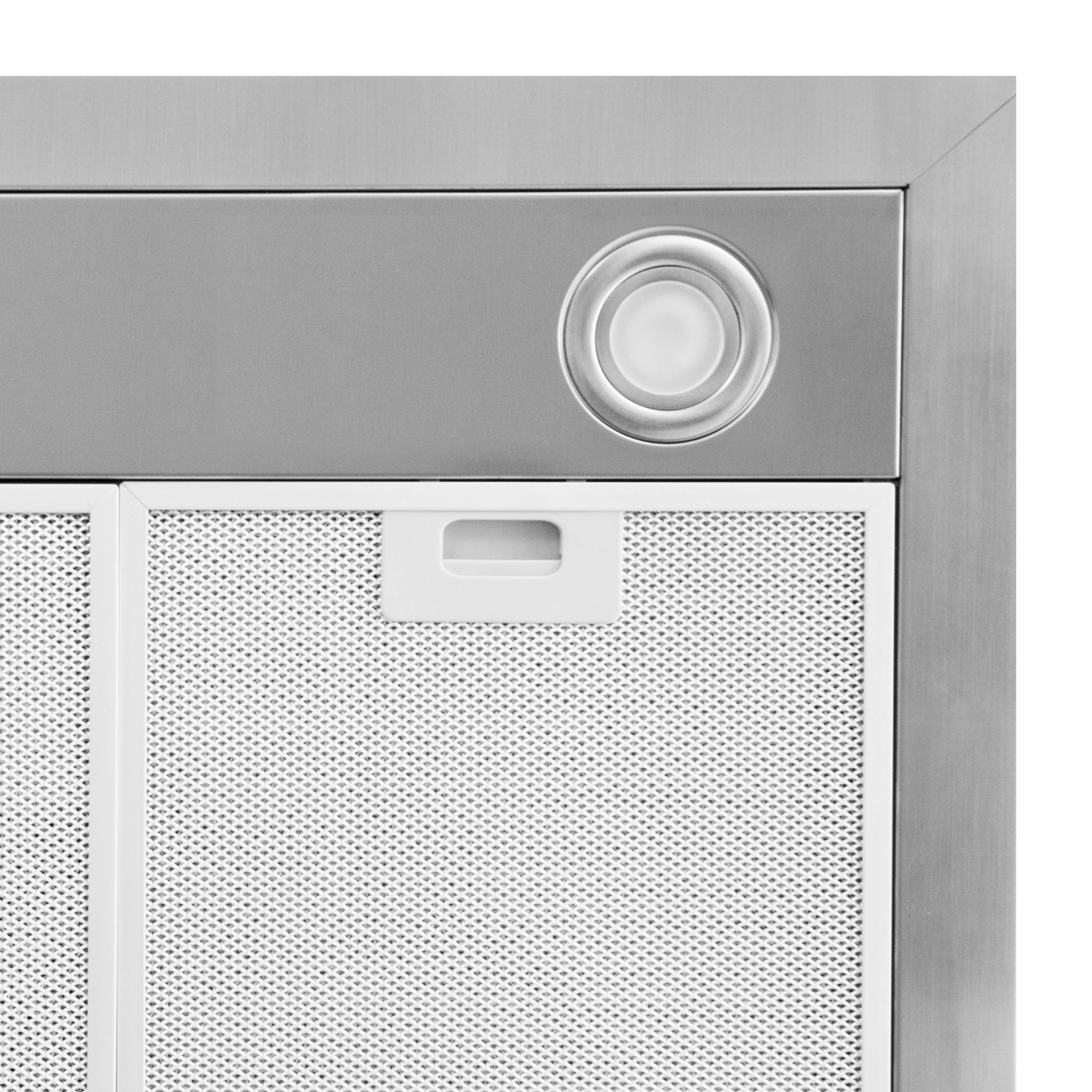 Gros plan d'une hotte aspirante en acier inoxydable. Elle a une lumière, un filtre blanc et une poignée. Le fond est blanc.
