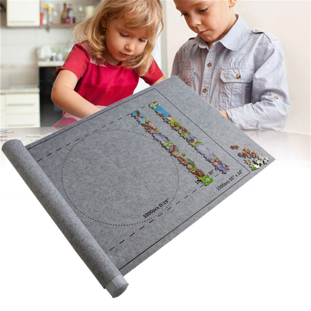 Zwei Kinder puzzeln auf einer grauen Matte. Die Matte hat Bereiche für das Puzzle, einige Teile sind bereits platziert.