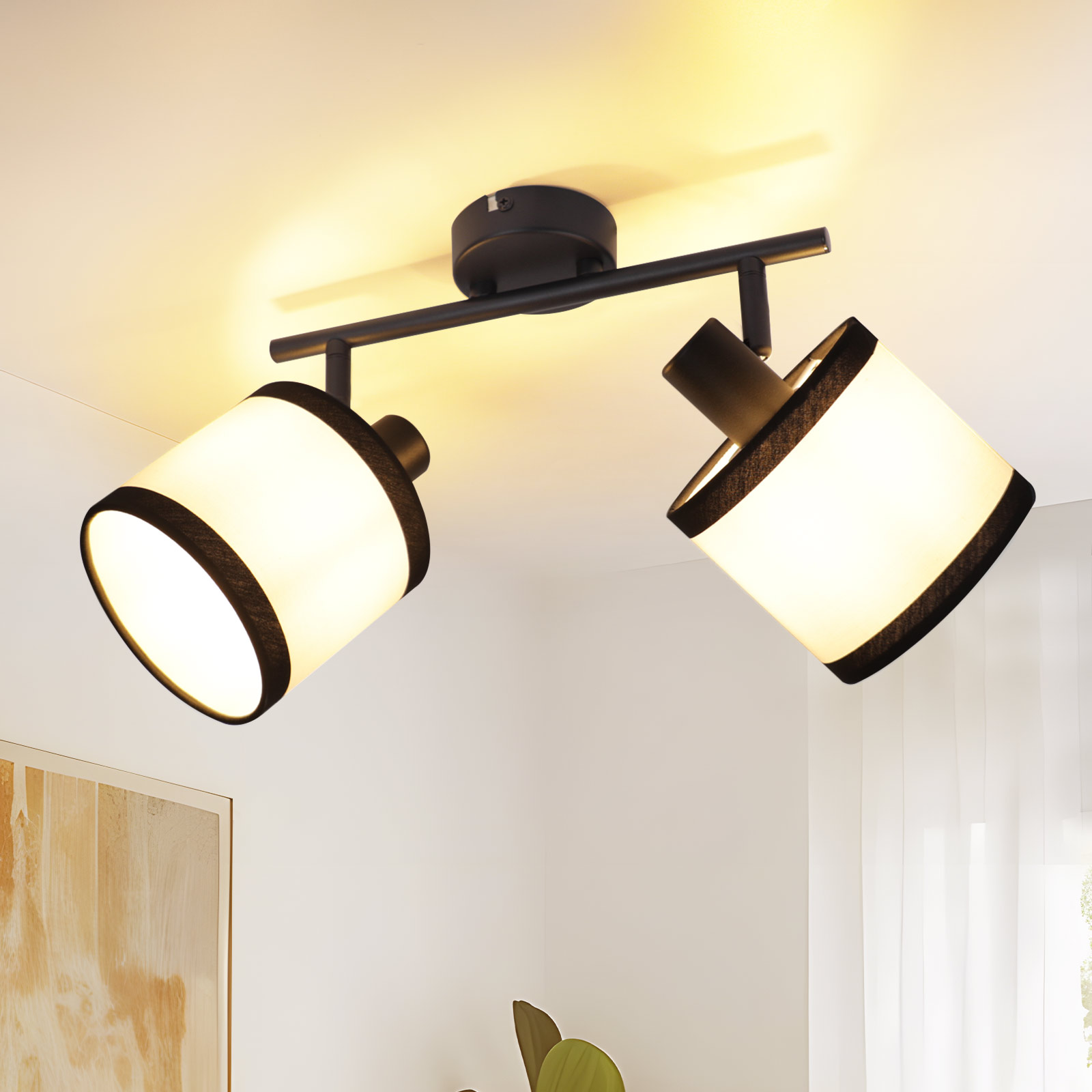 Eine schwarze Deckenleuchte mit zwei verstellbaren Lampen. Die Lampenschirme sind weiß mit schwarzem Rand und einer Glühbirne.